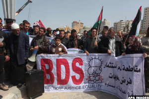 Palestinian fishermen hold banners in a protest to demand the boycott of the Israeli agricultural products, during the 10th annual Israeli Apartheid Week, at the seaport of Gaza City on March 16, 2014. Photo by Ashraf Amra